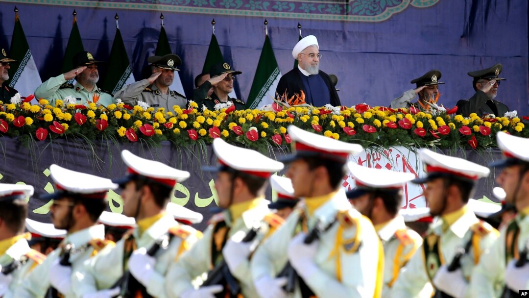 Iran's President Hassan Rouhani, top center, reviews army troops marching during the 38th anniversary of Iraq's 1980 invasion of Iran, in front of the shrine of the late revolutionary founder, Ayatollah Khomeini, outside Tehran, Iran, Sept. 22, 2018.