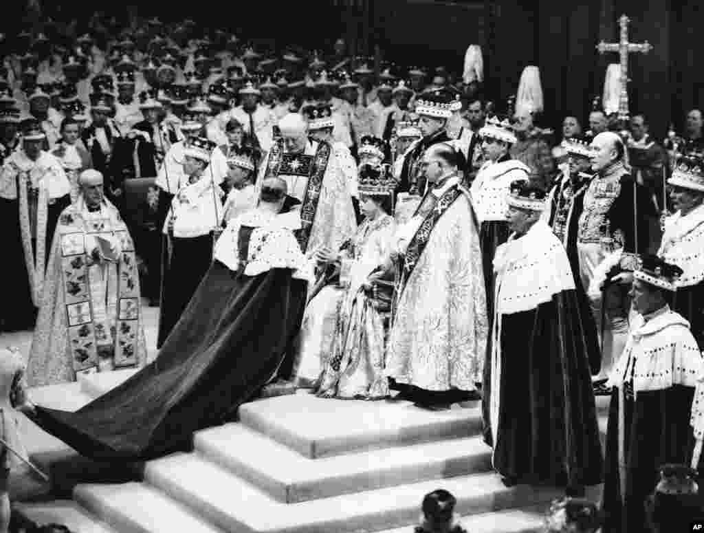 Surrounded by his clerics and ladies-in-waiting, Queen Elizabeth II sits in the Chair of Estate in Westminster Abbey, London, June 2, 1953, before being crowned.