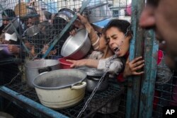 FILE - Palestinians seek food at Jabaliya refugee camp in the Gaza Strip, March 18, 2024.