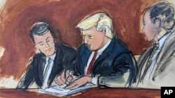 Former President Donald Trump, center, flanked by his defense attorneys, signs his bond in federal court, June 13, 2023, in Miami. (Elizabeth Williams via AP)