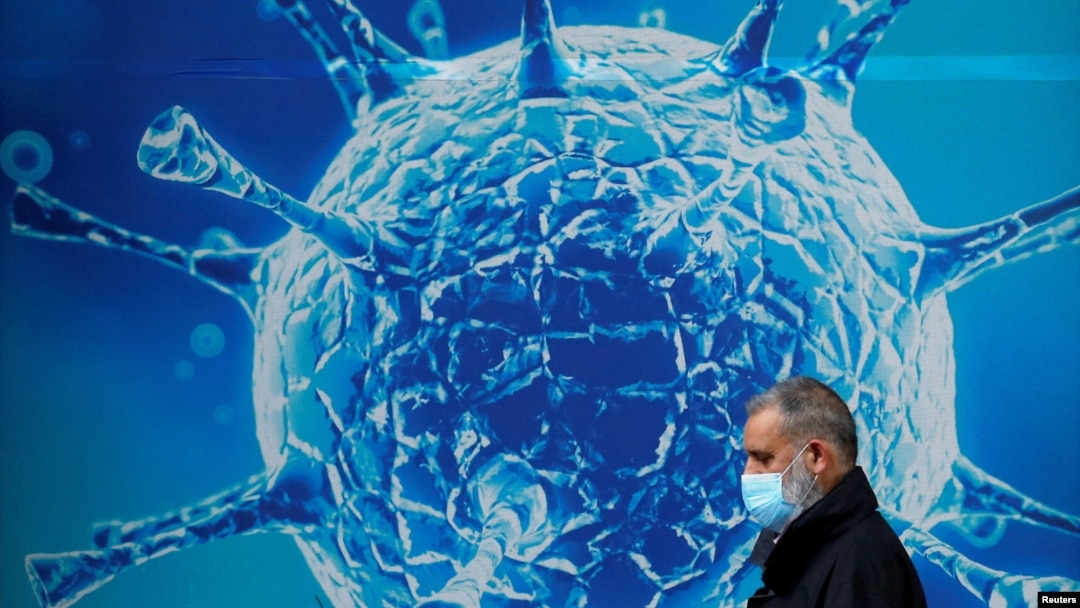 一名男子走過英國一家研究生物病毒的科研中心外的廣告牆。（2020年8月3日）