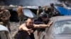 Trabajadores de emergencia y soldados empujan automóviles dañados después de que un misil ruso impactara un supermercado en Kostiantynivka, Ucrania, el 9 de agosto de 2024.