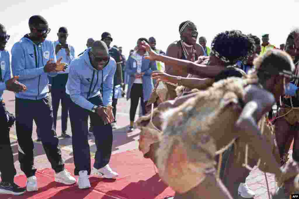 Olympic gold medalist Letsile Tebogo, 2nd left, dances with cultural dancers during a welcoming ceremony after winning the men's 200m athletics event during the Paris 2024 Olympic Games, at the Sir Seretse Khama International Airport in Gaborone. President Mokgweetsi Masisi declared Tuesday afternoon a holiday in honor of Tebogo.