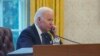 FILE - In this photo taken through a window, President Joe Biden talks on the phone in the Oval Office of the White House in Washington, Dec. 9, 2021. Biden spoke with Chinese President Xi 