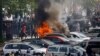 Učesnici protesta prolaze pored zapaljenih automobila u Nantu, u Francuskoj (Foto: REUTERS/Stephane Mahe)