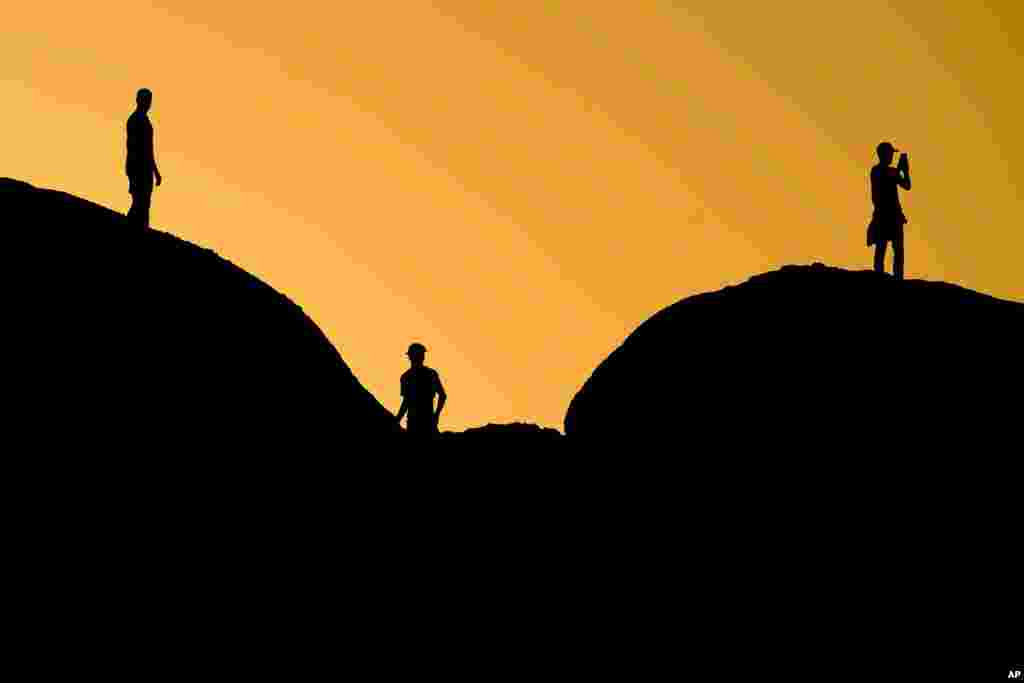 People are silhouetted against the sunset at Papago Park, Feb. 27, 2024, in Phoenix, Arizona.