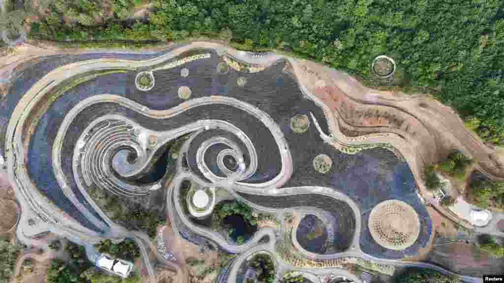 A drone view of a park transformed into a replica of Vincent Van Gogh's famous painting 'Starry Night,' featuring fields of lavender, shrubs, and lakes connected by an array of paths, in Visoko, Bosnia and Herzegovina.