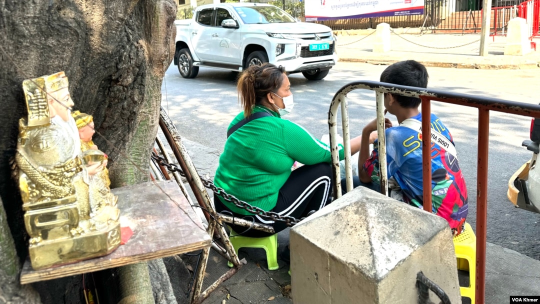 Lun Sam Ath, 45, with her son, Then Sithet, 10, sells face masks on a street in Phnom Penh, capital of Cambodia, April 5, 2024 (Sun Narin/VOA Khmer)
