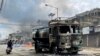 FILE - A person on a scooter rides past a damaged water tanker that was set afire during a protest by tribal groups in Churachandpur, in the northeastern Indian state of Manipur, May 4, 2023.
