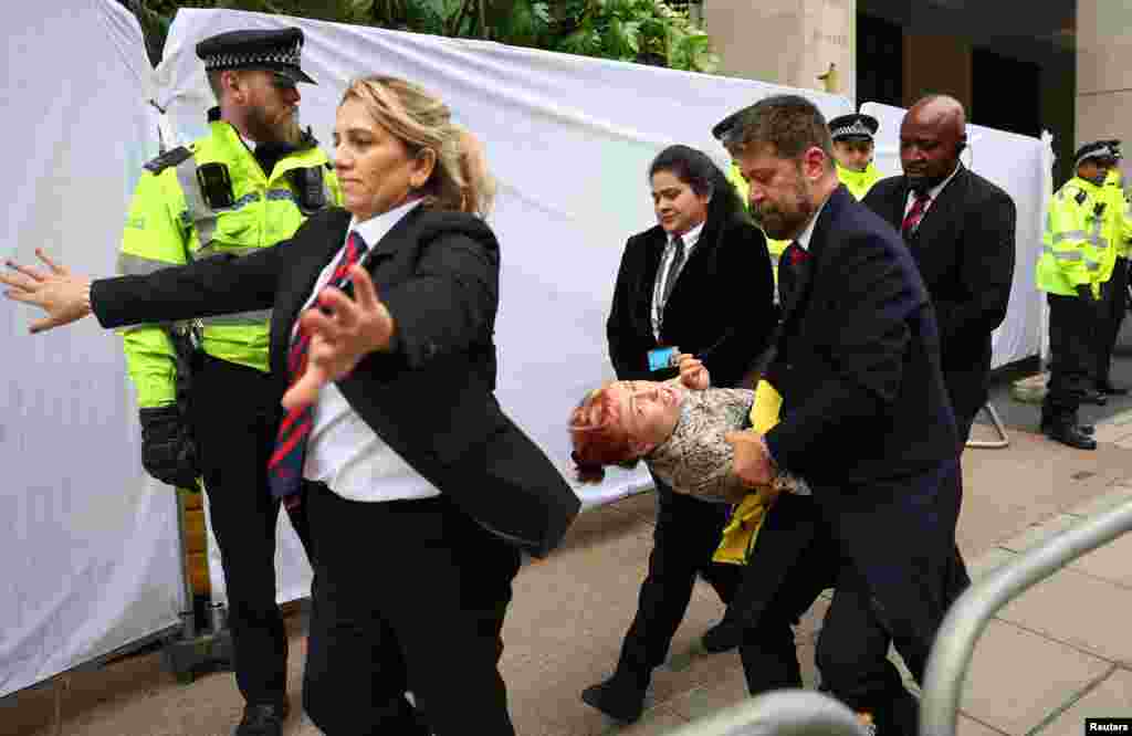 Police officers and security staff remove a demonstrator from the venue of the Energy Intelligence Forum, as Oily Money Out protests take place outside, in London. REUTERS/Toby Melville 