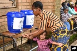 A child has her hands washed at a displacement center in Blantyre, southern Malawi March 16, 2023.