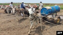 Men queue to fill tanks with water from a well in Gadaref, Sudan, on Aug. 17, 2023. For more than three months, millions have been rationing water and electricity, unable to reach the few health care facilities that still function in the country.