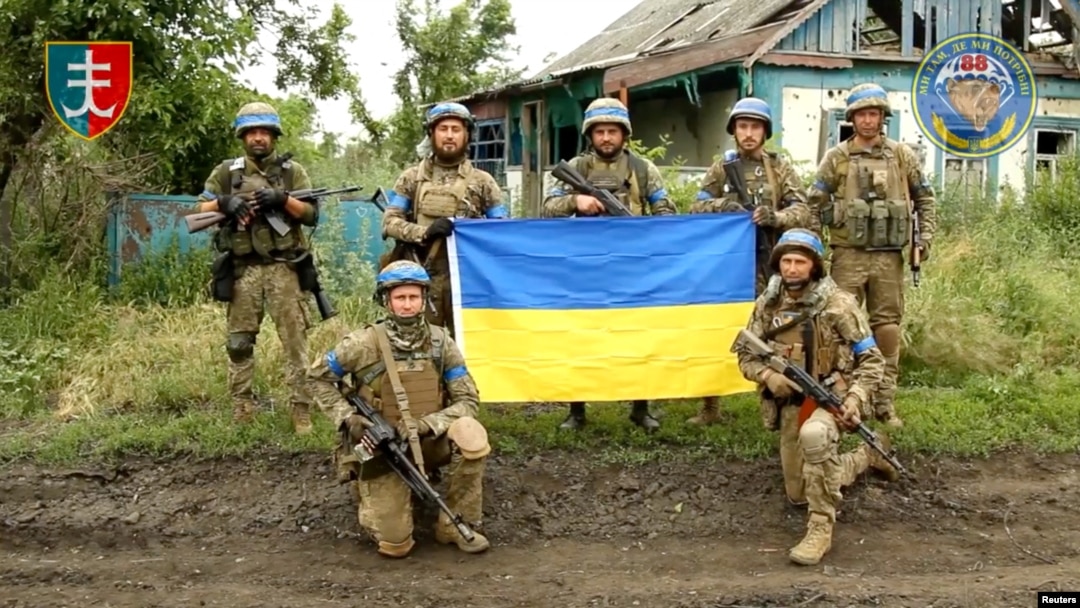 Ukrainian servicemen of the 35th Separate Brigade of Marines pose for a photograph with the Ukrainian flag in the liberated village of Storozheve, in Dontesk region, Ukraine, in the still image taken from a social media video released on June 12, 2023. 