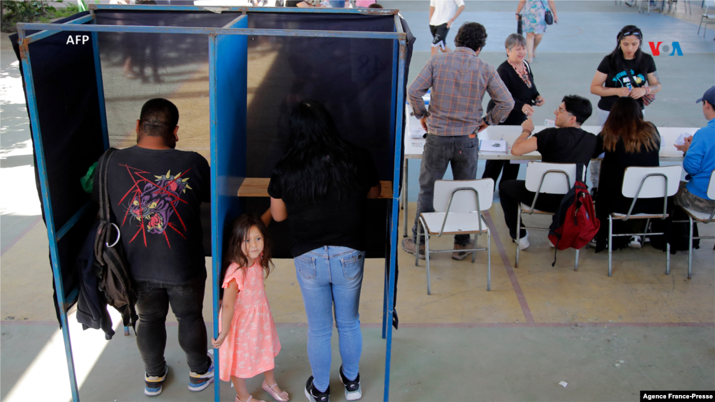 Una niña pequeña acompaña a una mujer que está votando en el refererendo sobre la nueva propuesta de constitución de Chile, el 17 de diciembre de 2023.