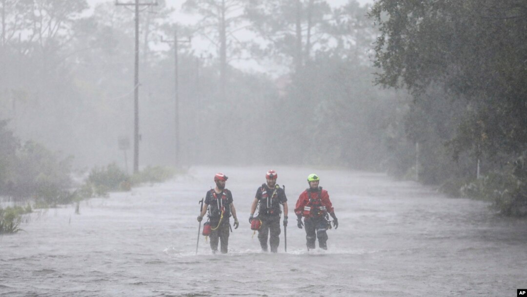 FILE - Rescue workers wade through a tidal surge on a highway while looking for people in need of help after the Steinhatchee River flooded, Aug 30, 2023, in Steinhatchee, Fla., following the arrival of Hurricane Idalia. 