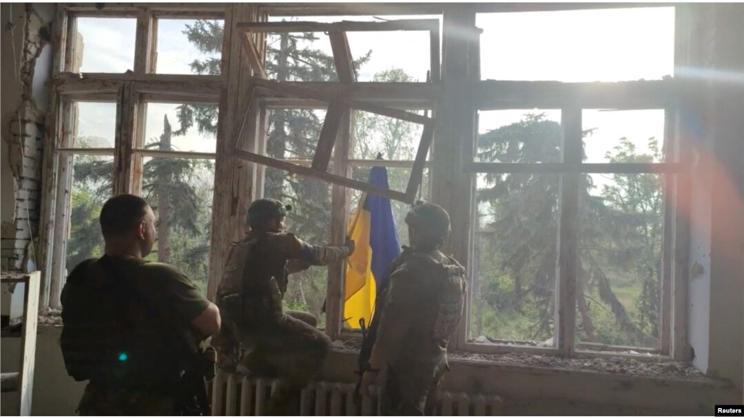Ukrainian soldiers place a flag at a building in a location given as Blahodatne, Donetsk Region, Ukraine, in this screengrab taken from a handout video released on June 11, 2023.