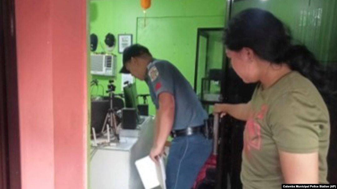 A policeman, left, inspects the area where a radio anchor was fatally shot by a man inside his home-based station in Calamba town in Misamis Occidenta province, southern Philippines, Nov. 5, 2023. 