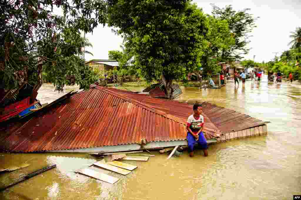 A villager sits on the roof of a flooded home in Lhokseumawe, Aceh, Indonesia.