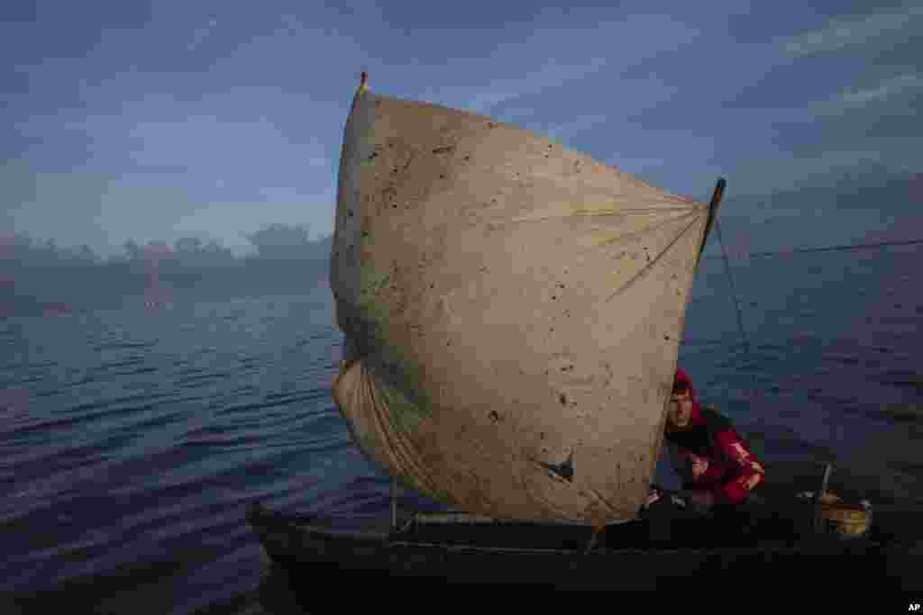 Yohandry Colina uses an oil-stained sheet for a sail on the boat he uses to put fish he catches in Lake Maracaibo in Cabimas, Venezuela, Oct. 12, 2022.