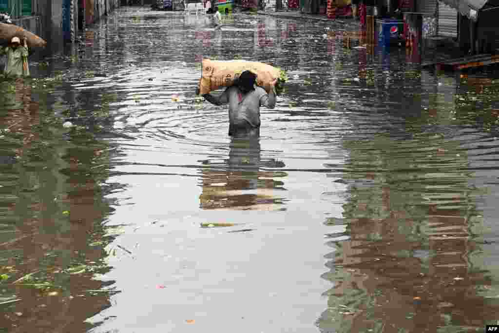 A vendor carrying a sack of leafy vegetables wades across a flooded market place after heavy rainfall in Lahore, Pakistan.