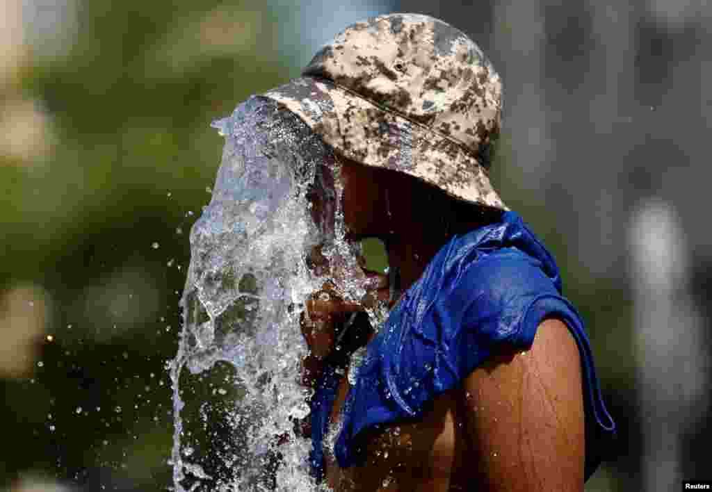 A boy refreshes himself at a fountain during a heatwave that is roasting Europe, in Brussels, Belgium.