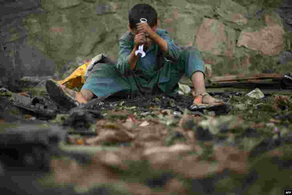 A child uses a wrench as he scavenges for scrap metal in Kabul, Afghanistan, July 26, 2022.