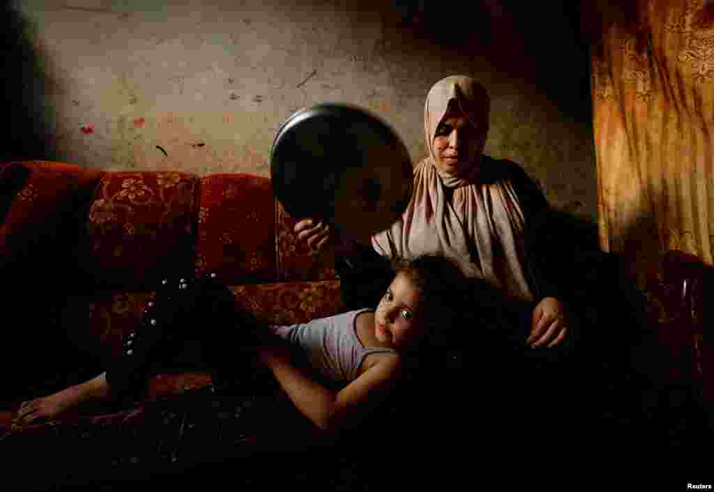A Palestinian woman fans her daughter with a tray amid a heatwave and lengthy power cuts in Gaza City, Aug. 1, 2022.