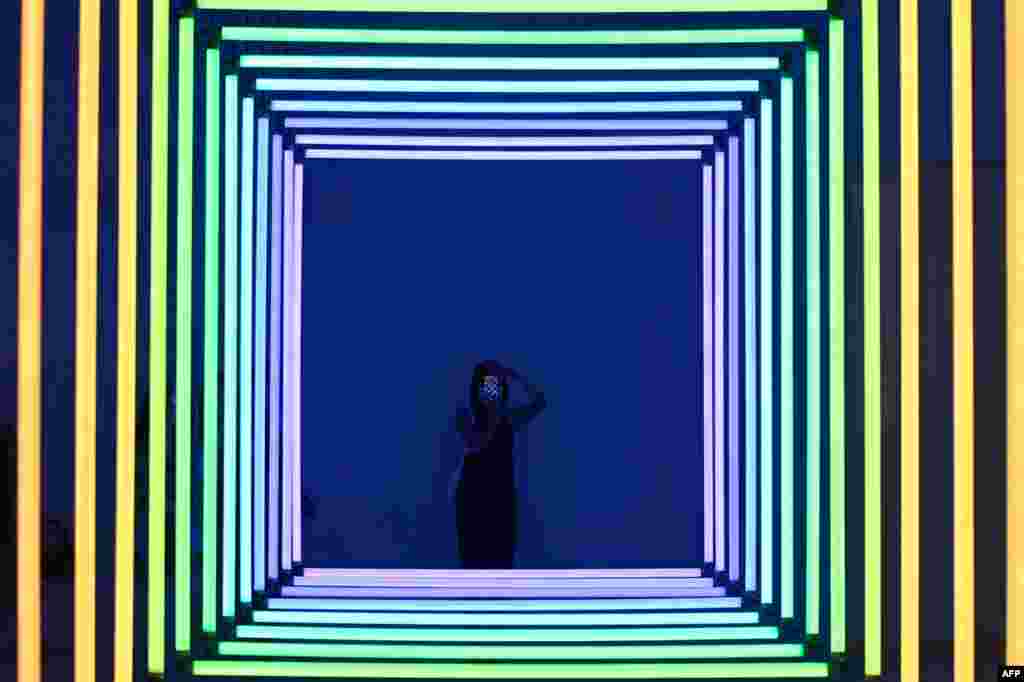 A woman uses her mobile phone to take a picture of Spectrum by Olivier Ratsi as she visits an exhibition at a museum in Beijing.