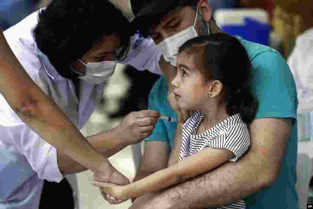 A girl gets a shot of the CoronaVac vaccine at a vaccination center in Rio de Janeiro, Brazil, on the first day of a COVID-19 vaccination campaign for children ages 3 and 4.