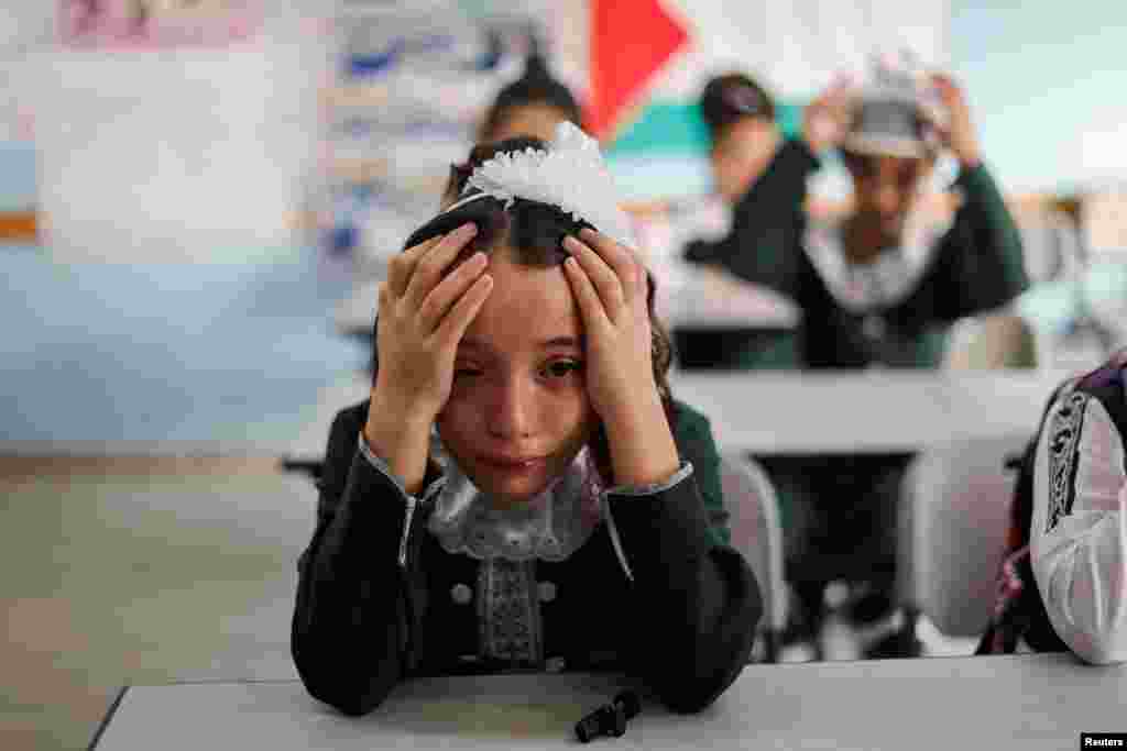 A classmate of Palestinian student Lian Al Shaer, 10, who was killed in recent Israel-Gaza fighting, reacts to Al Shaer's picture as a new school year begins, in Khan Younis in the southern Gaza Strip.