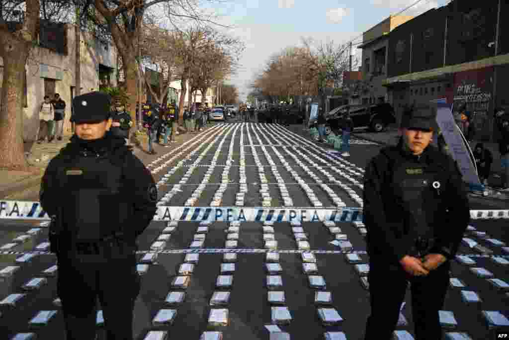 Police stand guard over seized packages of cocaine displayed to the press in Rosario, Santa Fe province, Argentina. Federal Police officers seized more than 1,600 kilos of cocaine, valued at some US$60 million, which were about to leave through the waterway to Dubai, authorities said. 