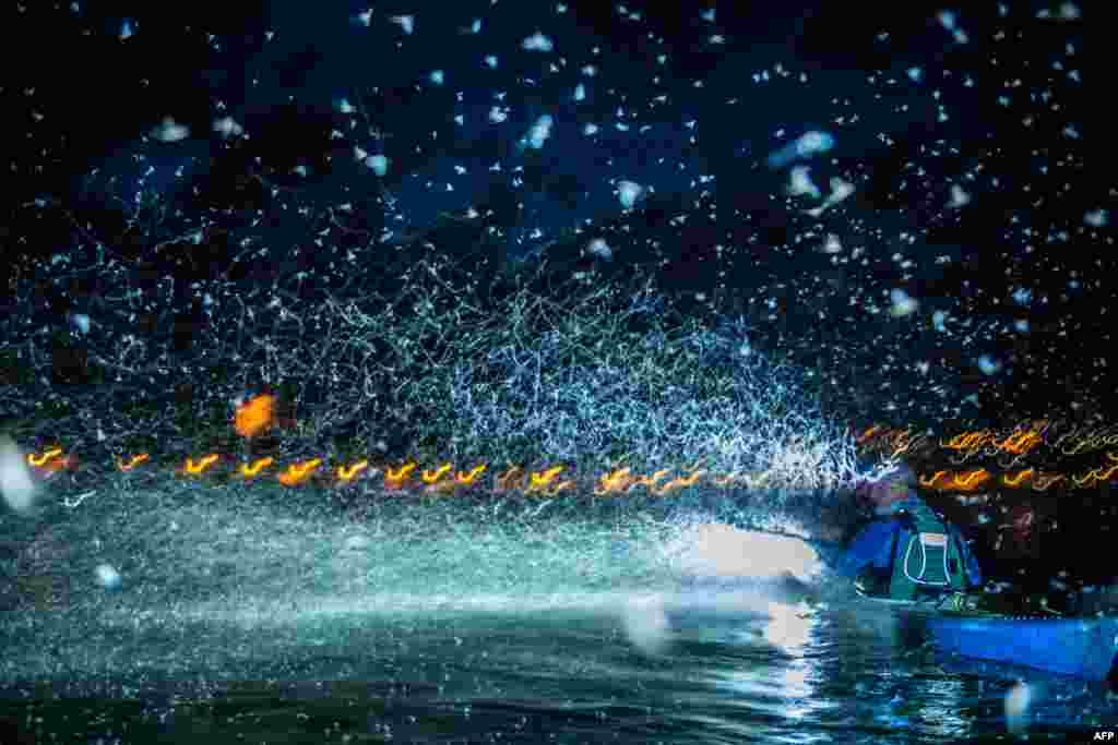 A swarm of mayflies insects flies by a boat over the surface of the River Danube after sunset in Szentendre, north of Budapest, Hungary, Aug. 9, 2022.