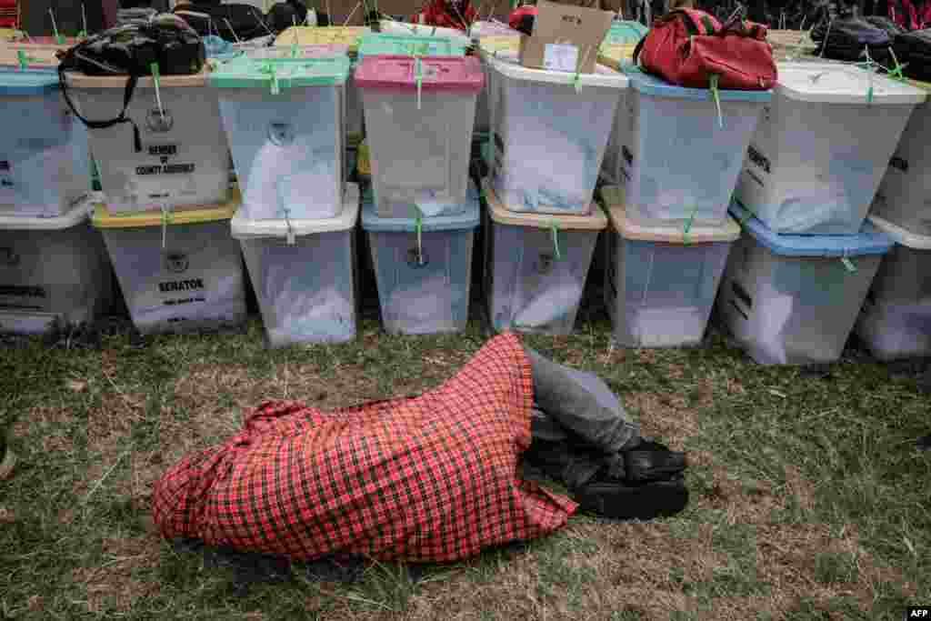 An election presiding officer sleeps next to ballot boxes as he waits to return all electoral materials following Kenya's general election at the tallying center in Kilgoris.