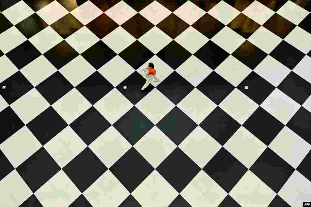 A woman walks past on a checkered floor at a mall in Bangkok, Thailand.