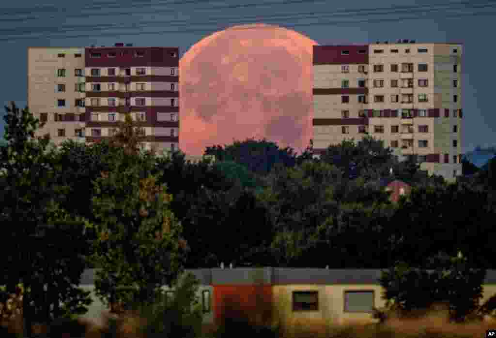 The full moon sets behind apartment houses in the outskirts of Frankfurt, Germany.