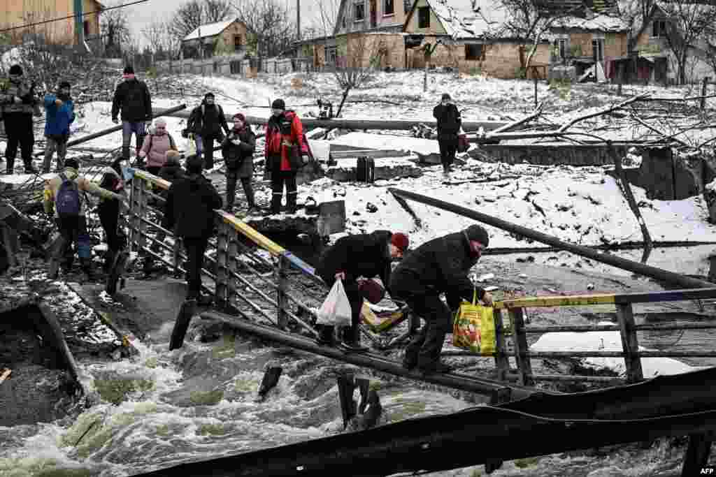 Kiyevda vayron qilingan ko'prikdan o'tayotgan fuqarolar. Ukraina Mudofaa vazirligi Rossiya tanklarining poytaxtga kirishiga yo‘l qo‘ymaslik uchun ko'prikni portlatgan. 