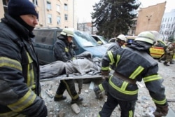 Rescuers carry the body of a victim on a stretcher outside the regional administration building, which city officials said was hit by a missile attack, in central Kharkiv on March 1, 2022. (Vyachesla Madiyevskyy/Reuters)