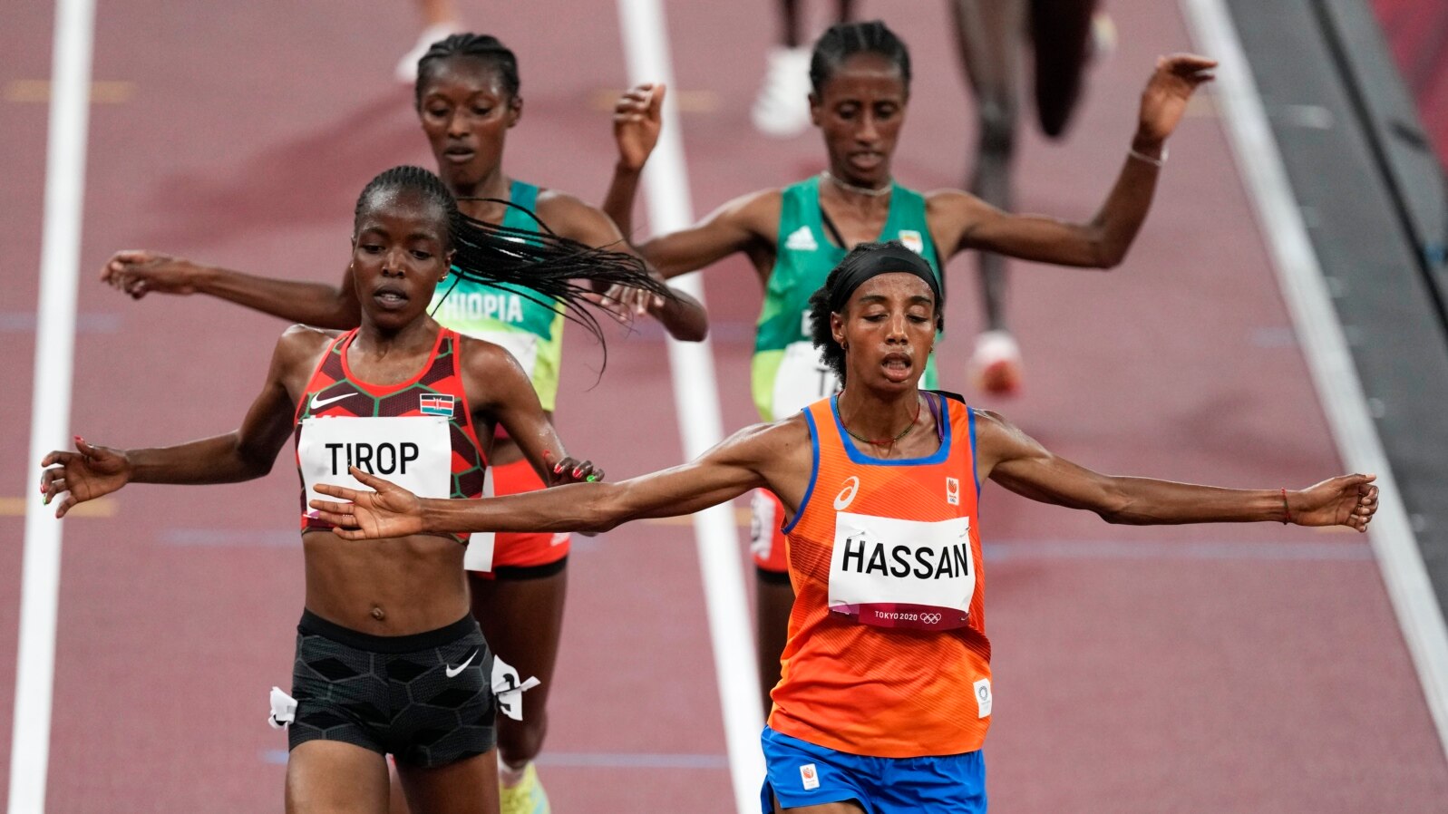 Sifan Hassan, of the Netherlands, foreground right, crosses the finish line ahead of Agnes Tirop, of Kenya, left, to win a heat in the women's 5,000-meter run at the 2020 Summer Olympics, July 30, 2021, in Tokyo. 