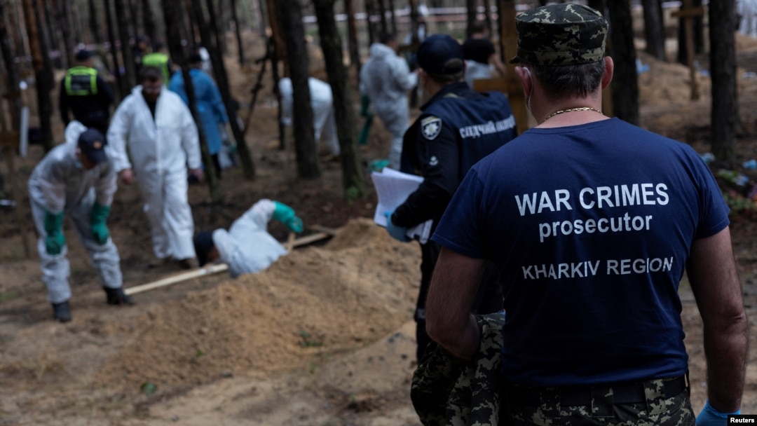 FILE - A war crimes prosecutor stands as experts work at a forest grave site during an exhumation, in the town of Izium, in Ukraine's Kharkiv region, Sept. 18, 2022, after Ukrainian forces pushed Russian troops from the town.