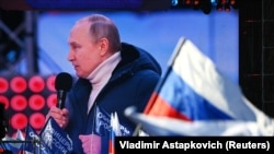 Russian President Vladimir Putin is seen on a screen as he delivers a speech during a concert marking the eighth anniversary of Russia's annexation of Crimea outside Luzhniki Stadium in Moscow, Russia March 18, 2022. (RIA Novosti/Vladimir Astapkovich via REUTERS)
