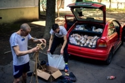 Alexii and Oleg Vadimovich prepare their car to deliver humanitarian aid in the districts of Kharkiv, eastern Ukraine, on April 26, 2022. (Dimitar Dilkoff/AFP)