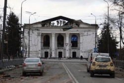 People walk past the Donetsk Academic Regional Drama Theater in Mariupol after a March 16, 2022, Russian airstrike on the building, which was being used as a bomb shelter. (Alexei Alexandro/Associated Press)