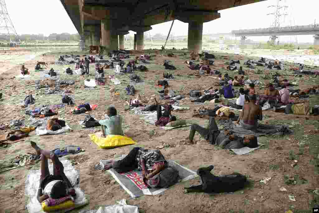 Homeless people sleep in the shade of an overbridge on a hot day in New Delhi, India.