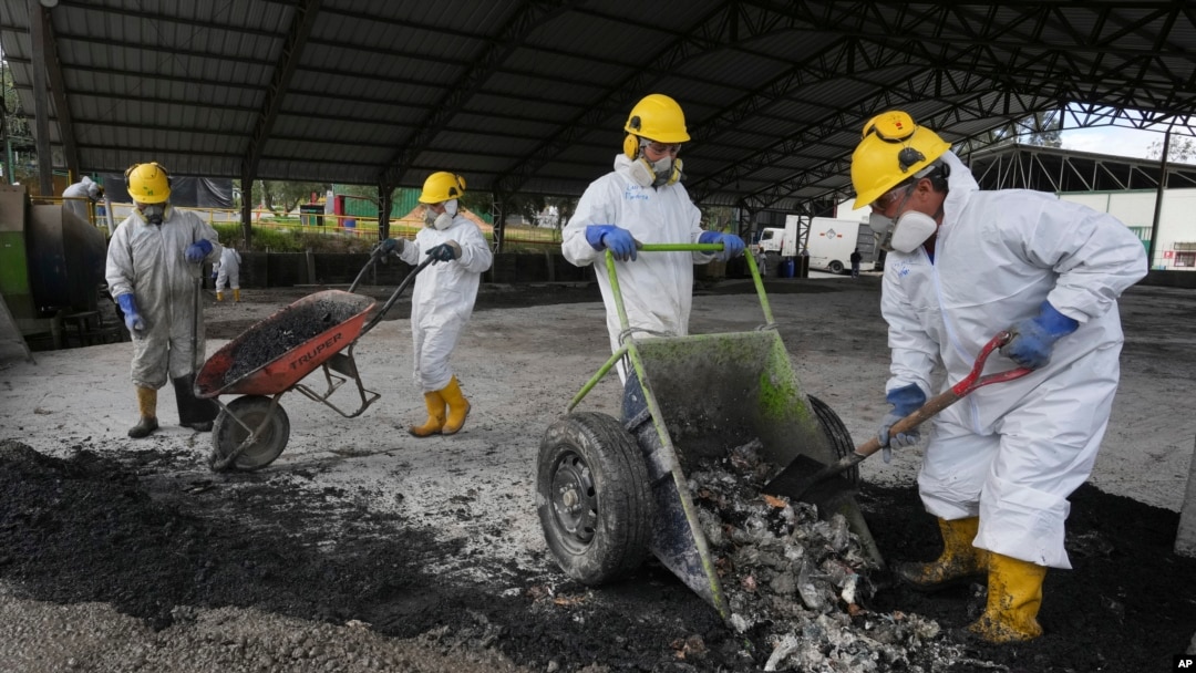 ARCHIVO - Trabajadores arrojan drogas incautadas mezcladas con productos de desecho para crear una capa de concreto, en una instalación en Cayambe, Ecuador, el viernes 3 de marzo de 2023.