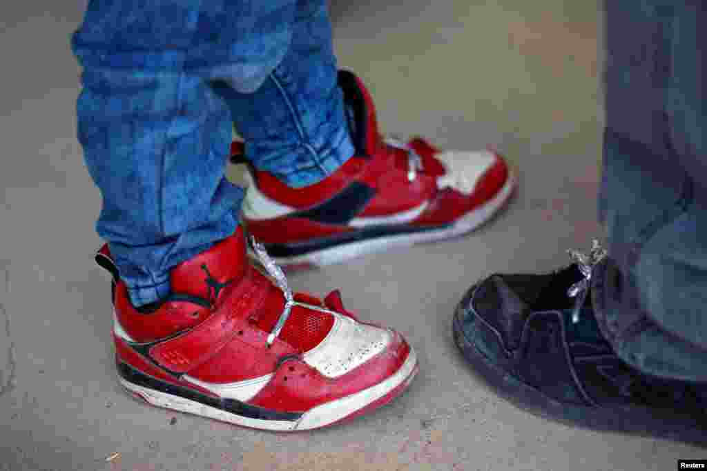 A little boy and his father wear shoelaces made out of foil blankets before entering a temporary shelter after illegally crossing with fellow Central American migrants the border between Mexico and the U.S., in Deming, New Mexico, U.S., May 16, 2019.