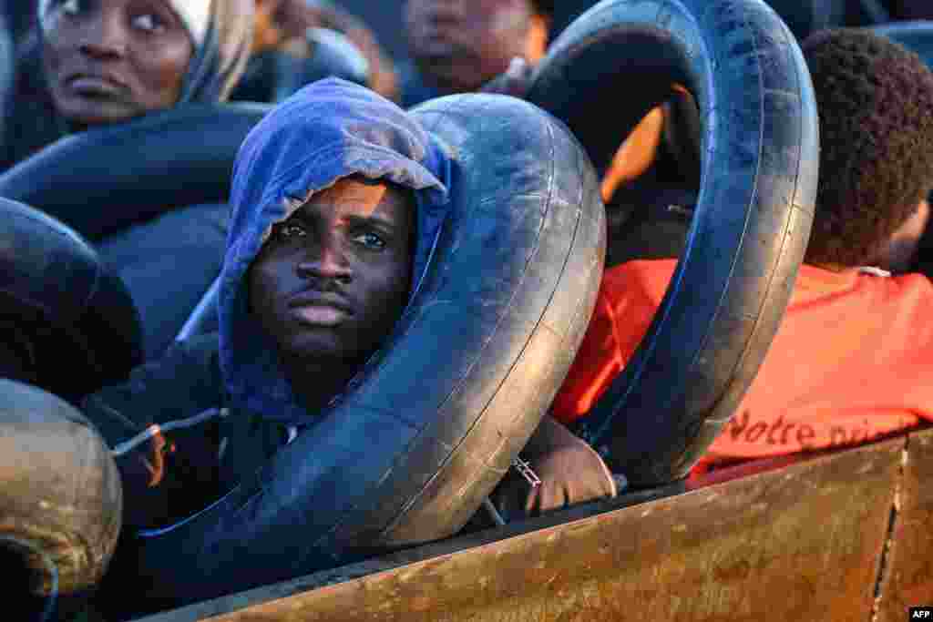 Migrants from sub-Saharan Africa sit in a makeshift boat that was being used to clandestinely make its way towards the Italian coast, as they are found by Tunisian authorities about 50 nautical miles in the Mediterranean Sea off the coast of Tunisia's central city of Sfax.