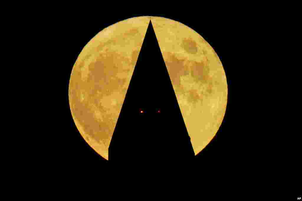 A full Hunter's moon rises behind the Washington Monument, in Washington, Oct. 9, 2022.