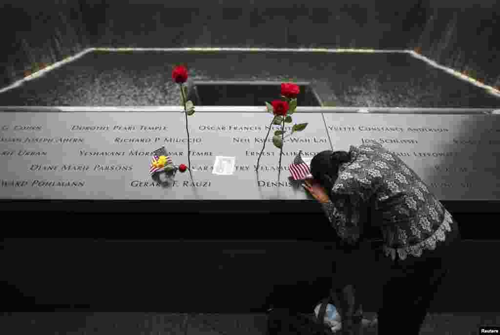 A woman grieves at the site of her husband's inscribed name at the edge of the North Pool during memorial observances on the 13th anniversary of the 911 attacks at the site of the World Trade Center in New York, Sept. 11, 2014.