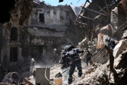 Workers from the self-proclaimed Donetsk People's Republic Emergency Situations Ministry clear rubble near the damaged Mariupol theater building on May 12, 2022. (Associated Press)