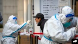 A worker swabs a man's throat for COVID-19 in Beijing, Nov. 17, 2022. Chinese authorities faced more public anger after lockdowns had been extended.